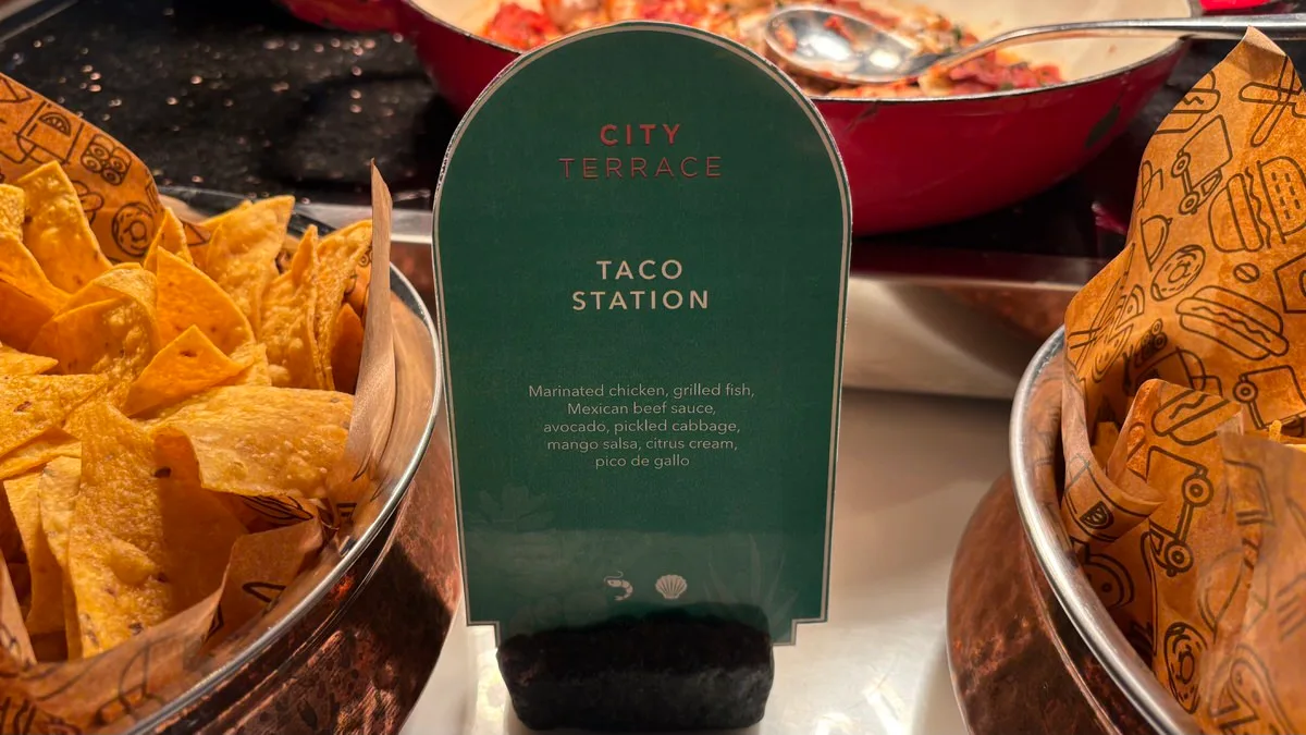 A green card headed City Terrace, reading Taco Station with a list of fillings and toppings, between two copper bowls of tortilla chips