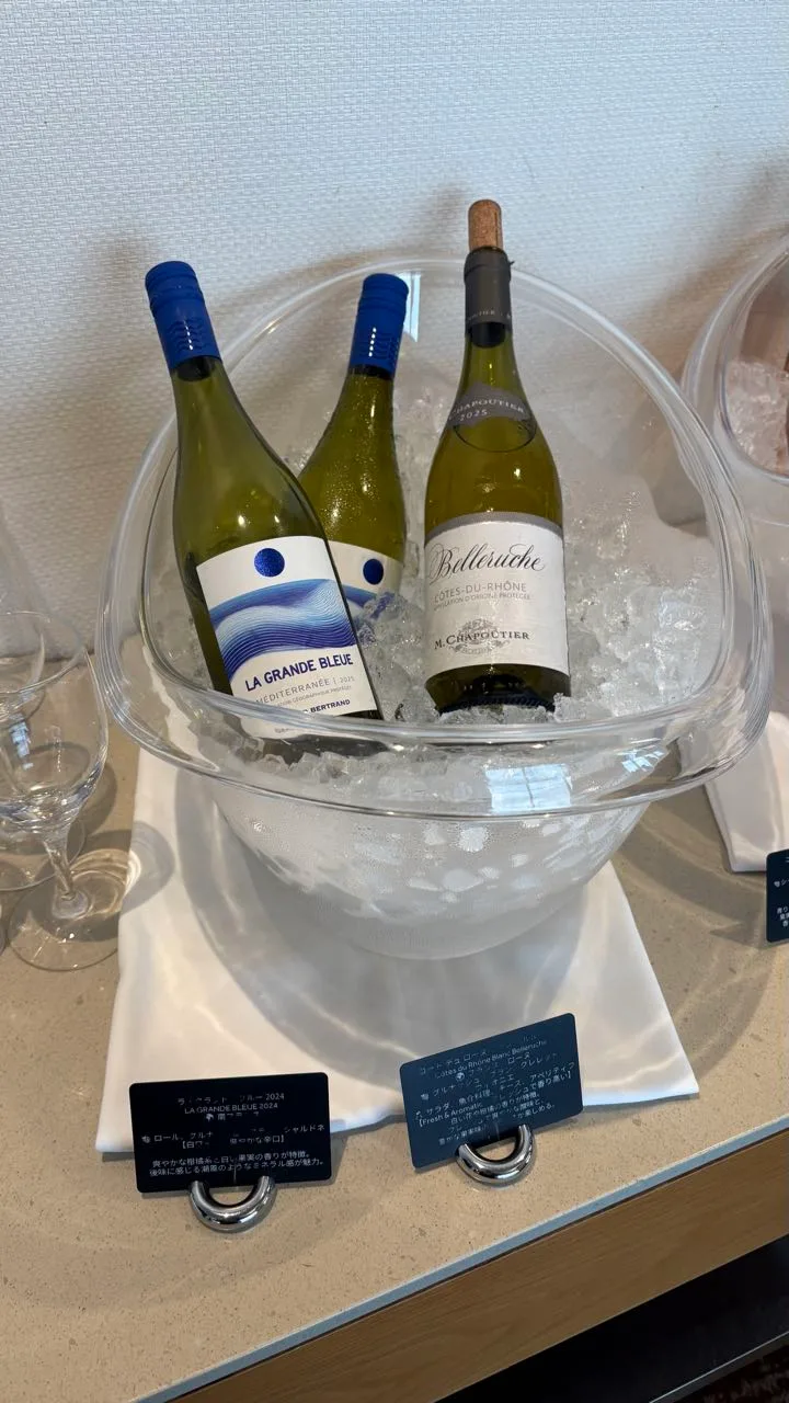 Bottles standing in a glass bowl of crushed ice, the front one labelled LA GRANDE BLEUE with a blue and white label, and M. Chapoutier Belleruche Côtes-du-Rhône beside it, tasting cards on the counter below
