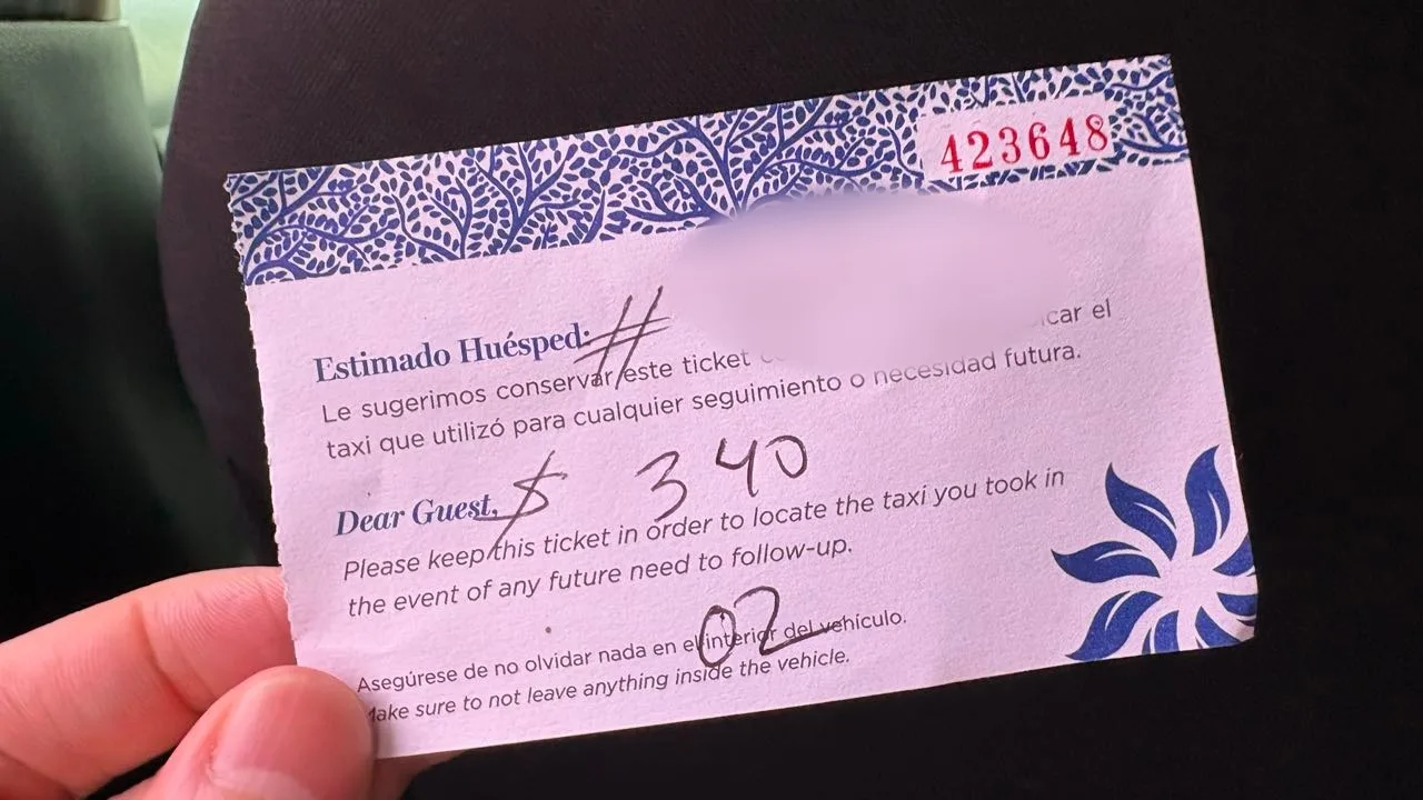 A hand holding a small printed taxi ticket numbered 423648 with 340 and 02 written on it in pen